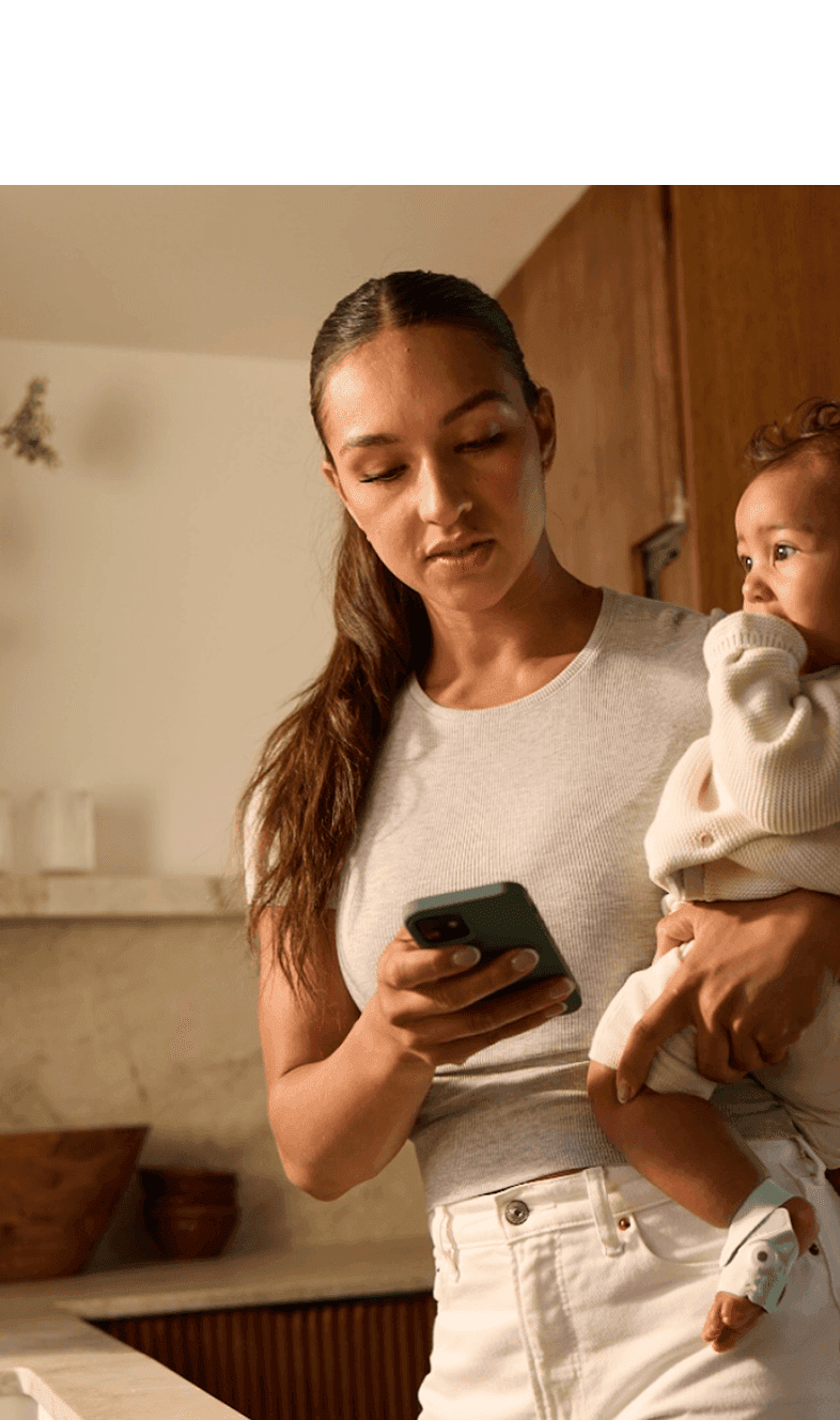 Woman holding baby while using phone